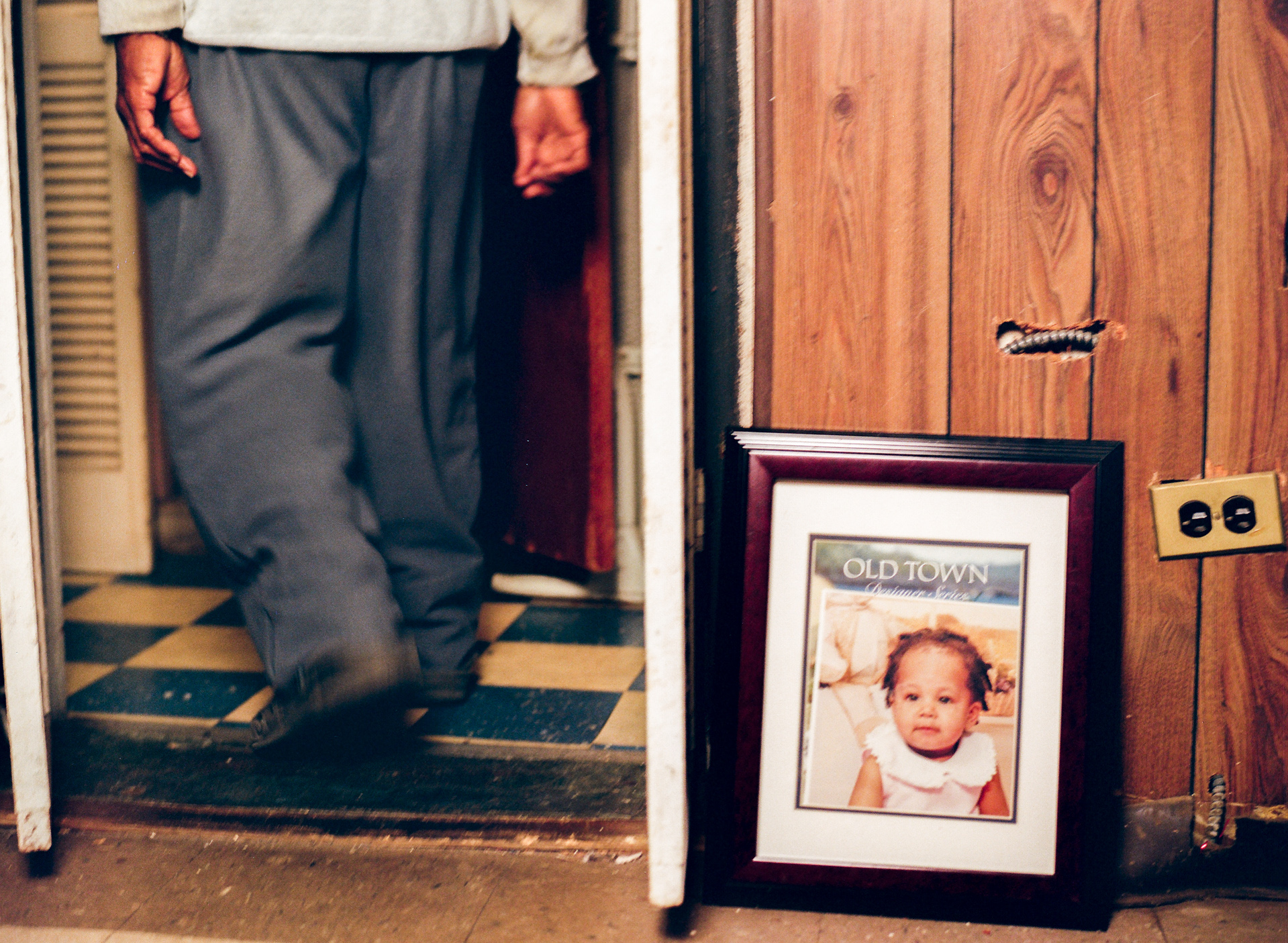 Man's legs in a doorway next to a framed photo of a child
